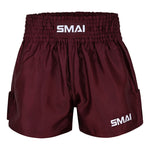 Burgundy satin polyester Muay Thai Shorts by SMAI, featuring a thick elastic waistband and white SMAI logos on the waistband and left leg, displayed against a plain white background. These unisex shorts combine style and comfort, making them ideal for all fighters.