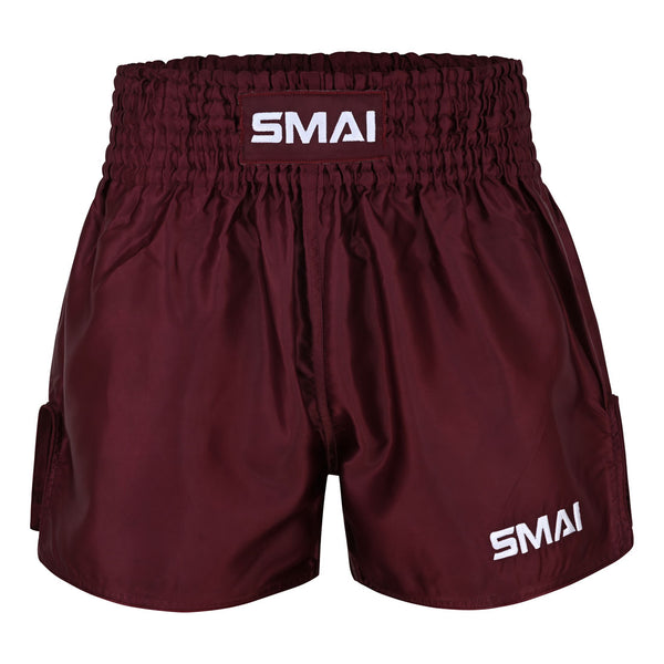 Burgundy satin polyester Muay Thai Shorts by SMAI, featuring a thick elastic waistband and white SMAI logos on the waistband and left leg, displayed against a plain white background. These unisex shorts combine style and comfort, making them ideal for all fighters.