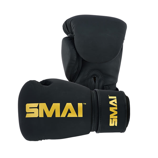 Two SMAI PRE ORDER - Gold Series Boxing Gloves in black/gold, featuring the brand name in bold gold letters on the wrist. One glove stands upright, the other lies horizontally, both on a white background. Premium quality for serious athletes.