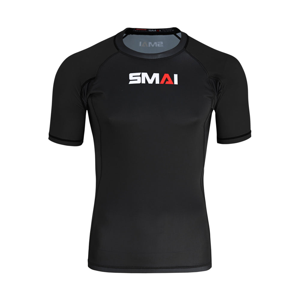 The SMAI Short Sleeve Rash Guard - Black is an athletic compression shirt with white and red branding on the chest, ideal for BJJ or no-gi grappling, shown on a plain white background.