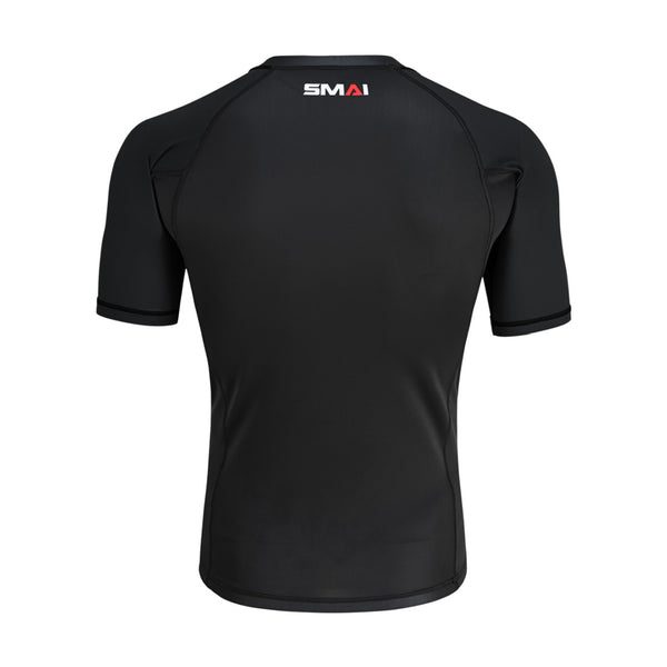 The SMAI Short Sleeve Rash Guard - Black is shown from the back, featuring a white and red "SMAI" logo below the collar. Its fitted design and black stitching make it ideal for BJJ or no-gi grappling.