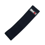 A black resistance band from the Firm Recovery & Stretch Pack, ideal for toning glutes, displays a rectangular label featuring the SMAI brand in red and white. Set against a white background, it emphasizes the band's straightforward and practical design.