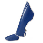 The SMAI Essentials Muay Thai Shin Instep Guard in blue, made from synthetic leather with white trim, offers superior shin and instep protection and is shown standing upright against a white background.