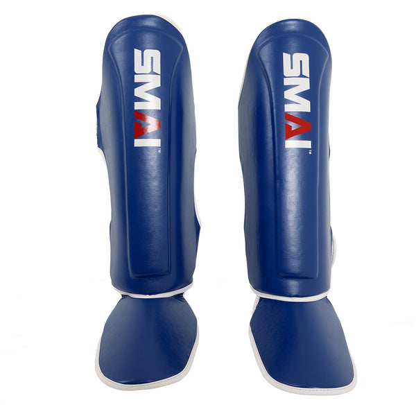The Essentials Muay Thai Shin Instep Guard - Blue by SMAI features blue synthetic leather, white trim, and the SMAI logo in white and red, offering superior shin and instep protection for martial arts training.