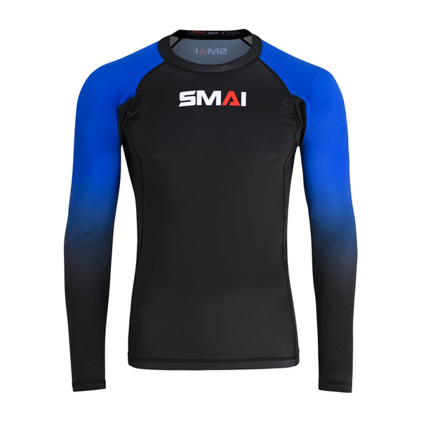 The SMAI Long Sleeve Rash Guard - Blue features a black body, blue gradient sleeves, and white/red "SMAI" chest branding. Designed for no-gi grappling with advanced compression technology. Shown on a plain white background.