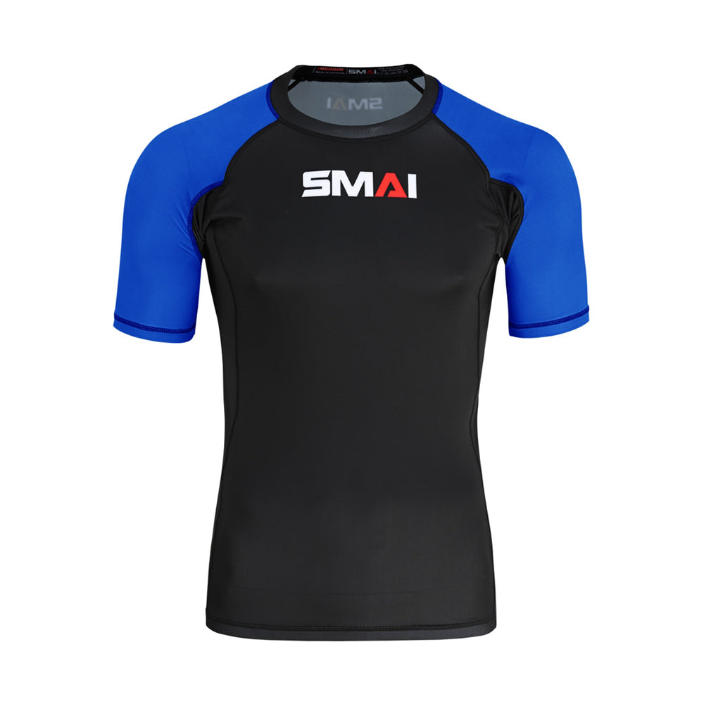 The SMAI Short Sleeve Rash Guard - Blue features a black body, blue sleeves with dark blue trim, and "SMAI" in white and red on the chest—perfect for no-gi grappling or use as a compression shirt.