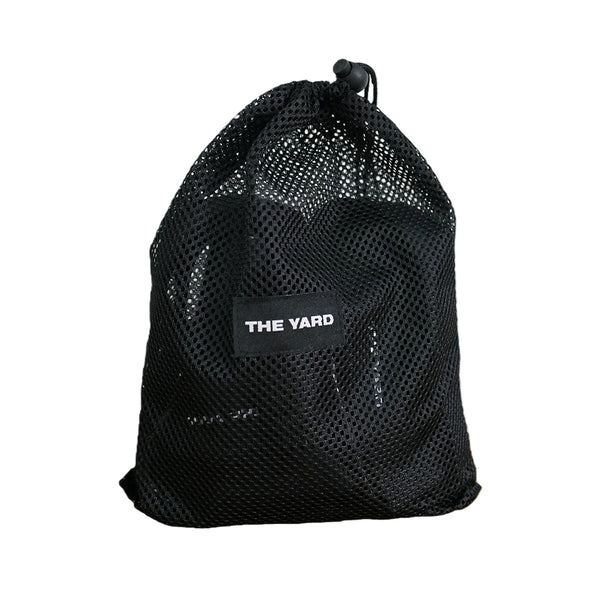 A black mesh drawstring bag labeled "THE YARD" in white text sits against a white background. It contains the SMAI The Yard - Suspension Trainer - GTS, ideal for portable functional strength training wherever you go.
