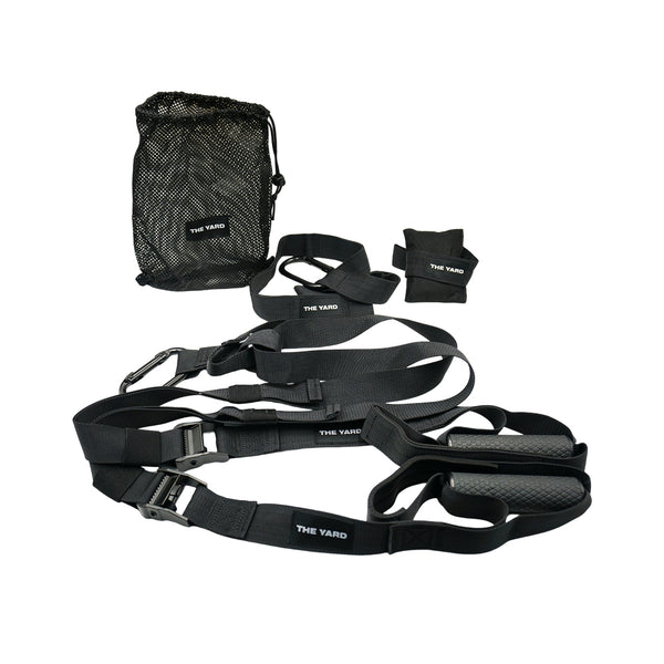 The SMAI The Yard - Suspension Trainer - GTS set features black straps with handles, adjustable loops, metal clips, a mesh bag, and two "THE YARD" ankle/wrist straps—ideal portable gear for functional strength training.