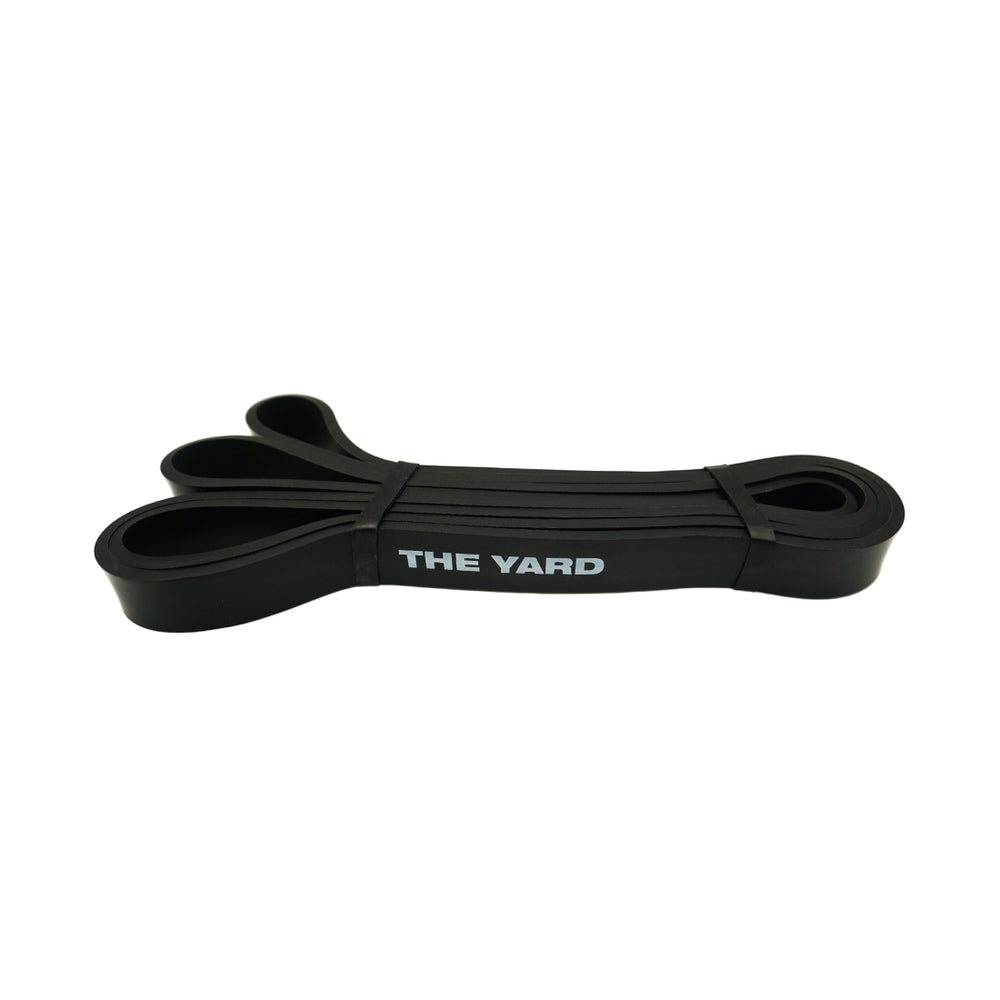 The SMAI The Yard Exercise Resistance Band - 25lb/11.3kg in black displays "THE YARD" in white text and is coiled neatly on a plain white background—a high-quality resistance band ideal for strength training.