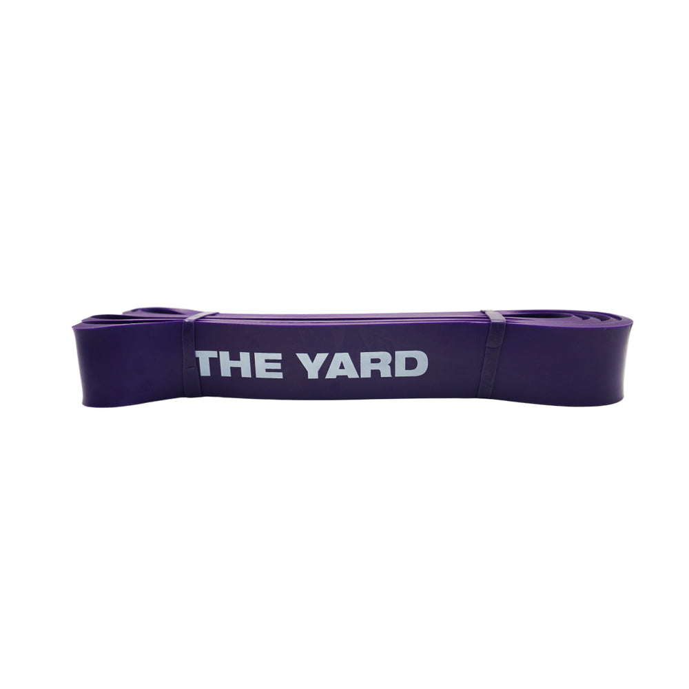 The SMAI The Yard Exercise Resistance Band (50lb/22.6kg) in purple, featuring "THE YARD" printed in white, is folded compactly on a plain background—ideal for adding to your fitness band collection.