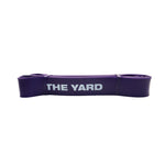 The SMAI The Yard Exercise Resistance Band (50lb/22.6kg) in purple, featuring "THE YARD" printed in white, is folded compactly on a plain background—ideal for adding to your fitness band collection.