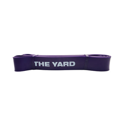 The SMAI The Yard Exercise Resistance Band (50lb/22.6kg) in purple, featuring "THE YARD" printed in white, is folded compactly on a plain background—ideal for adding to your fitness band collection.