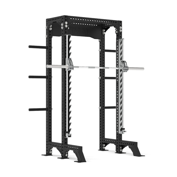 The SMAI Half Power Rack with Smith Machine from the Vanta Series features a durable black frame with numerous holes for adjustable height settings and handy side pegs for organizing weights, highlighting its adaptable design. A barbell is securely positioned on the safety pins inside the rack, embodying the strength of the Vanta Series.