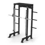 The Half Power Rack with Smith Machine from the Vanta Series by SMAI is a stylish black metal unit designed for weightlifting exercises, complete with a barbell and weight plates. It includes multiple adjustment holes, safety catches, and storage pegs for additional weights.