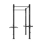 Introducing the SMAI The Yard - Rig - 2 Cell: a black metal power rack designed for strength training. This freestanding rig features adjustable holes, a pull-up bar on top, and integrated dip bars attached to its sides for versatile workouts. Supported by four sturdy legs, it offers multiple exercise options with built-in dip stations.