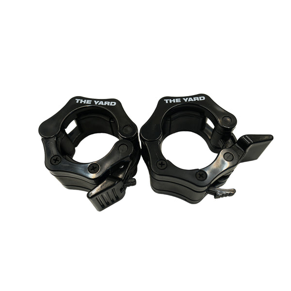 A pair of SMAI The Yard - Barbell - Easy Lock 50mm Collars (black) feature locking levers to securely hold weight plates. These durable collars are shown side by side on a white background.