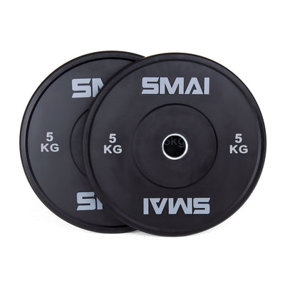 A pair of SMAI Home Gym Bumper Plates - 5kg, featuring sleek black design and clear SMAI branding, are stacked with one slightly overlapping the other against a white background—ideal for any home gym setup.