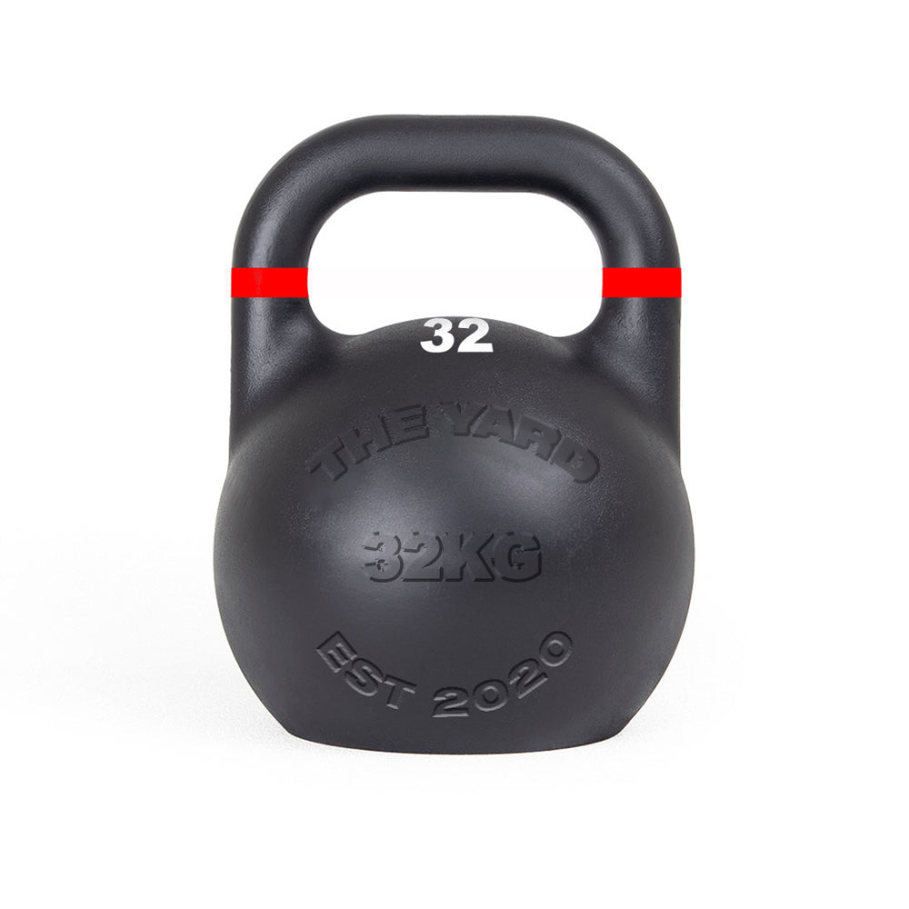The SMAI The Yard - Competition Steel Kettlebell 32kg is black with a red stripe near the handle, features "THE YARD 32KG EST 2020" embossed on the front and "32" in white below the handle, and has a consistent size design.
