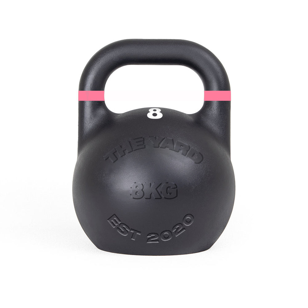 The Yard - Competition Steel Kettlebell 8kg by SMAI is a black, custom-branded kettlebell with a pink stripe near the handle and "THE YARD 8KG EST 2020" embossed on the front, designed to competition standards.