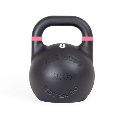 The Yard - Competition Steel Kettlebell 8kg by SMAI is a black, custom-branded kettlebell with a pink stripe near the handle and "THE YARD 8KG EST 2020" embossed on the front, designed to competition standards.