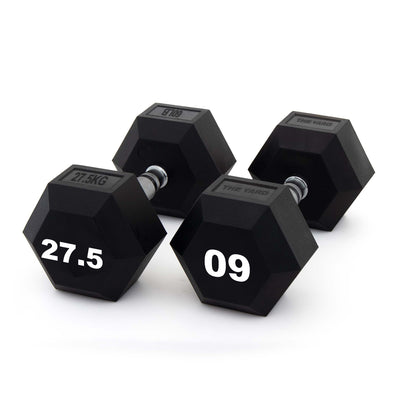 Four SMAI The Yard - Rubber Hex Dumbbells (27.5kg, black) are arranged on a white surface; two show their weight marking "27.5," while the other rubber-coated dumbbells display the brand labels.