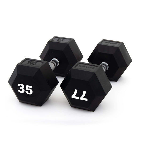 Three black hexagonal dumbbells, including the SMAI The Yard - Rubber Hex Dumbbell 35kg (Pair), are shown on a white background. The weights read “35KG,” “35,” and “11,” each with a metal handle and black rubber-coated ends—ideal for commercial gyms.