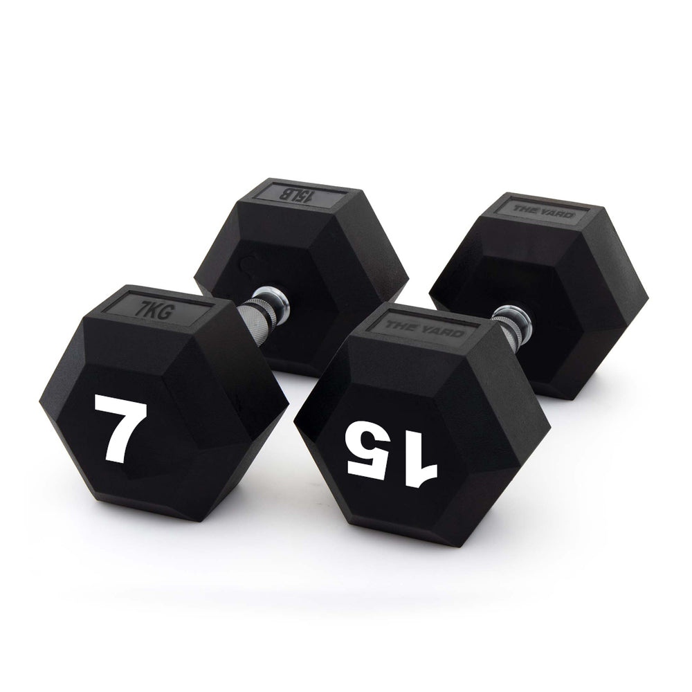 Three black SMAI The Yard - Rubber Hex Dumbbell 7kg pairs are arranged on a white surface, each marked "7 KG" in bold white numbers and designed with an ergonomic grip for comfortable commercial gym use.