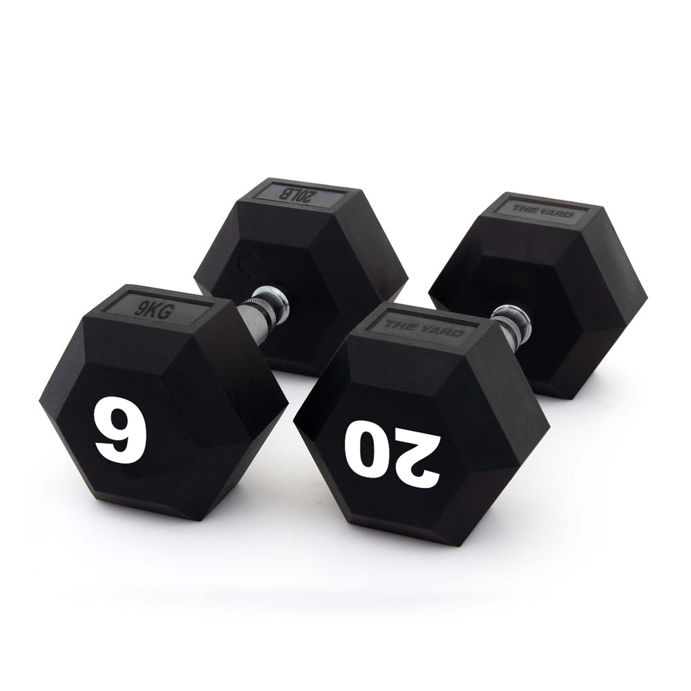 Three black SMAI The Yard - Rubber Hex Dumbbells with metal handles are arranged on a white background. Two commercial gym dumbbells display "9 KG" and "20 KG" in large white numbers on their ends.
