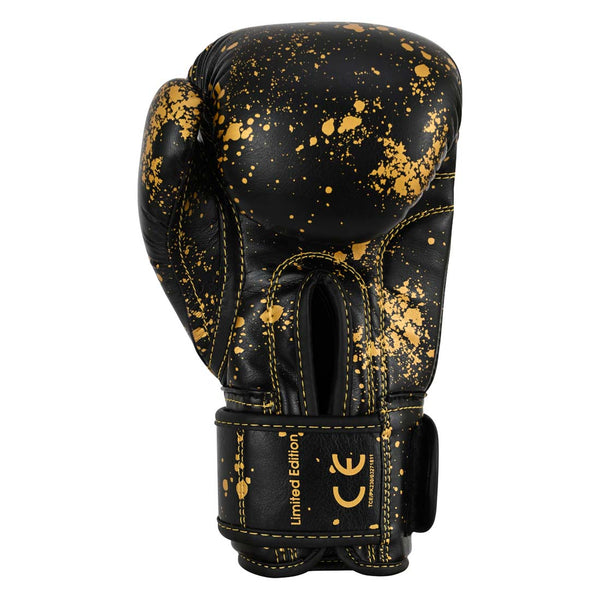 SMAI Essentials Kids Boxing Glove - Black/Gold Dragon, featuring black youth boxing gloves with a gold paint splatter pattern, gold stitching, and “Limited Edition” and “CE” printed on the wrist strap.