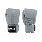 The SMAI Elite85 Boxing Glove in Charcoal features quality cowhide leather, black wrist straps, "SMAI" branding, and a "12oz" weight mark. One glove is palm down and one is palm up, showcasing the craftsmanship and branded details.