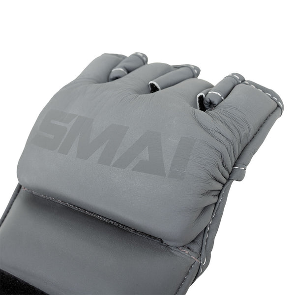 A close-up of SMAI Elite85 MMA Gloves in charcoal cowhide leather with exposed fingers and white stitching, featuring the brand name "SMAI" on the padded top—perfect for professional training.