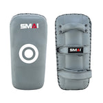 Two charcoal Elite85 Muay Thai Pads V2 by SMAI are pictured—one with a white target circle, the other with two grip handles and an arm strap. Both feature impact absorbing foam for optimal training sessions and display the SMAI logo at the top.