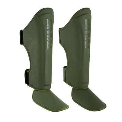 The SMAI PRE ORDER: Elite85 Muay Thai Shin Guards in olive green feature foot protection and velcro straps, designed for martial arts or sports, displayed against a white background.