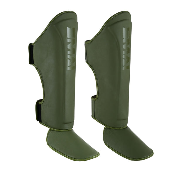 The SMAI PRE ORDER: Elite85 Muay Thai Shin Guards in olive green feature foot protection and velcro straps, designed for martial arts or sports, displayed against a white background.
