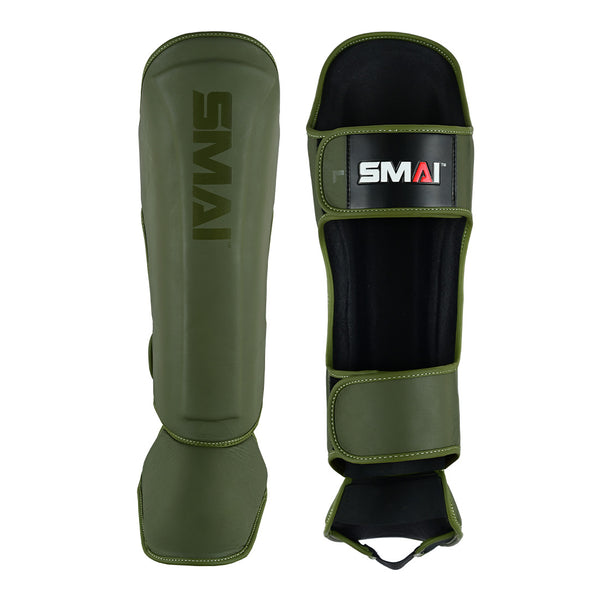 Two olive green SMAI Elite85 Muay Thai shin guards are shown: one displays the logo, while the other reveals adjustable straps and interior padding, emphasizing their lightweight design.