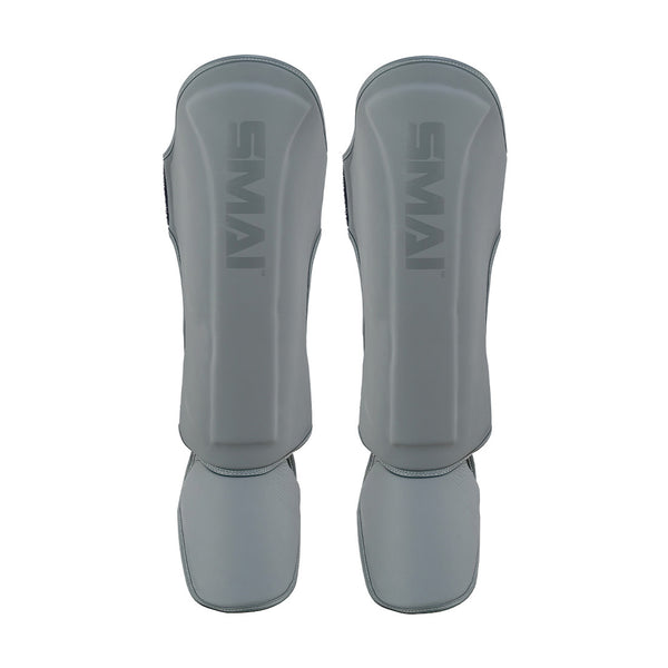The SMAI Elite85 Muay Thai Shin Guards in charcoal are lightweight with padded protection for shins and feet, making them ideal for Muay Thai training.