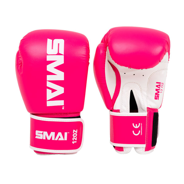 The Essentials Boxing Glove - Pink by SMAI features bright pink training gloves with white branding, white palm accents, and a Velcro strap labeled "12 OZ," shown from both the front and palm side.
