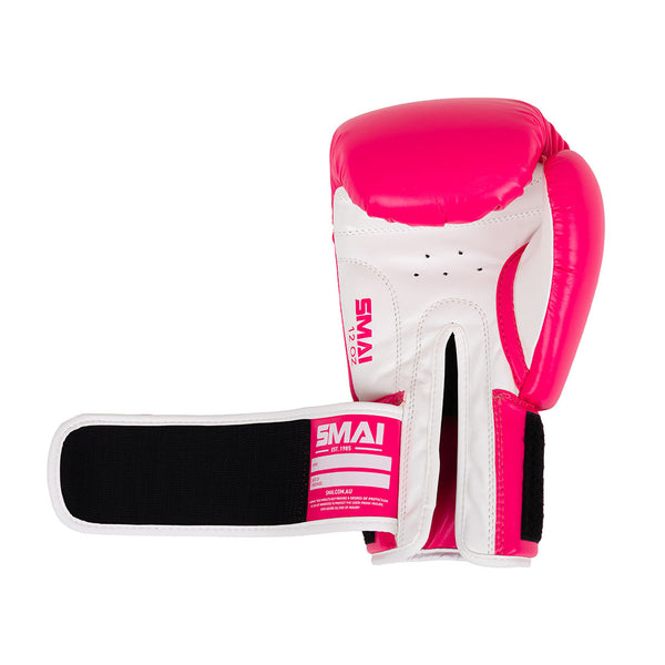 The SMAI Essentials Boxing Glove - Pink features a pink and white design with a black and white adjustable wrist strap, ideal for training, displayed on a plain white background.