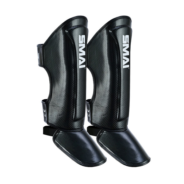 The Essentials Muay Thai Shin Guards Kids - Black by SMAI, shown upright on a white background, are ideal protective shin guards for kids’ martial arts and sports gear.
