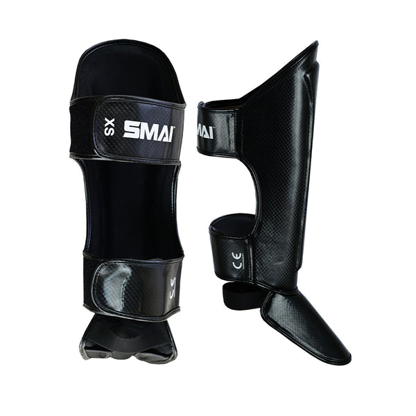 The Essentials Muay Thai Shin Guards Kids by SMAI in black feature foot protection, adjustable straps, and the white SMAI logo—perfect sports gear to keep kids safe and comfortable during training.