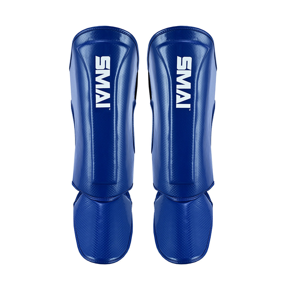 A pair of SMAI Essentials Muay Thai Shin Guards for kids in blue, featuring durable protection and white "SMAI" branding on the shin, shown side by side against a white background.