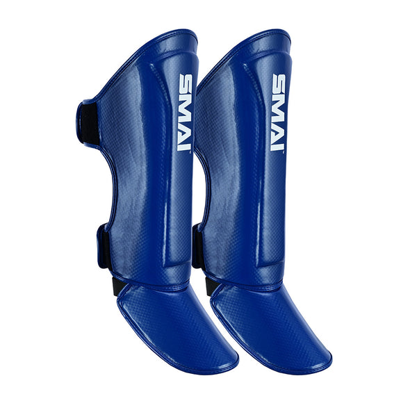 Introducing the Essentials Muay Thai Shin Guards Kids - Clearance Line by SMAI. These blue shin guards for children feature attached foot protection and display the white SMAI logo. Designed with adjustable black straps to secure them around the leg, they are an ideal choice of shin guards for young Muay Thai enthusiasts.