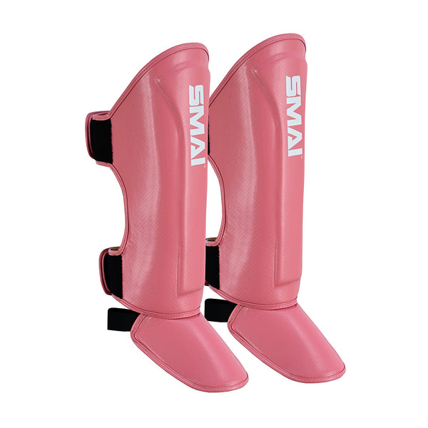 The Essentials Muay Thai Shin Guards Kids - Pink by SMAI feature black straps and a white "SMAI" logo, providing durable shin protection as part of children's martial arts or sports protective gear.
