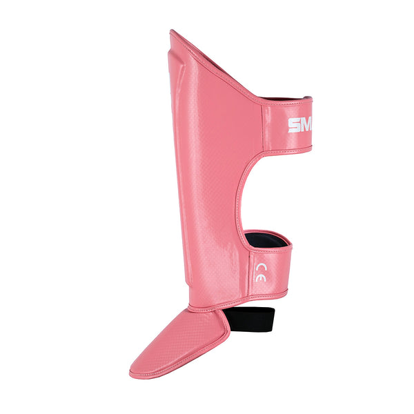The SMAI Essentials Muay Thai Shin Guards Kids - Pink offer durable shin protection with foot protectors, adjustable straps, and a glossy finish, making them ideal and comfortable martial arts gear for children.
