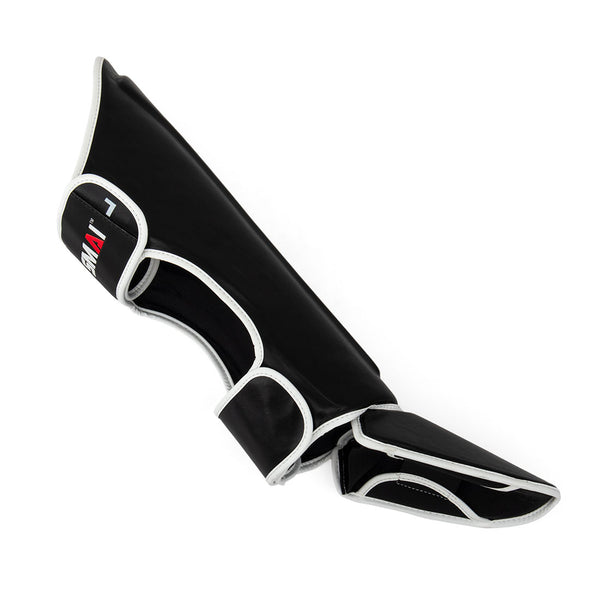 The Essentials Muay Thai Shin Guards - Kids by SMAI are black with white trim and are pictured on a white background. Specially designed for sports protection, these shin guards include a foot cover and an adjustable strap, making them an excellent choice for kids’ martial arts.