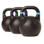 Three SMAI Competition Kettlebell - Fusion Series kettlebells are arranged in a row on a white background. Each black ergonomic kettlebell features a colored band—green, purple, or blue—around the handle and has the SMAI brand name embossed on the front.