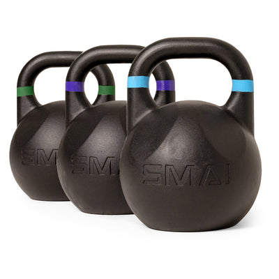 Three SMAI Competition Kettlebell - Fusion Series kettlebells are arranged in a row on a white background. Each black ergonomic kettlebell features a colored band—green, purple, or blue—around the handle and has the SMAI brand name embossed on the front.
