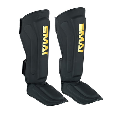 A pair of PRE ORDER - Gold Series Muay Thai Shin Guards in black/gold by SMAI, featuring yellow branding and multi-layered shock absorption for martial arts protection.