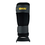 The PRE ORDER - Gold Series Muay Thai Shin Guards in Black/Gold by SMAI feature a gold logo, multi-layered shock absorption, adjustable straps, and padding for full shin and foot protection—ideal for martial arts.