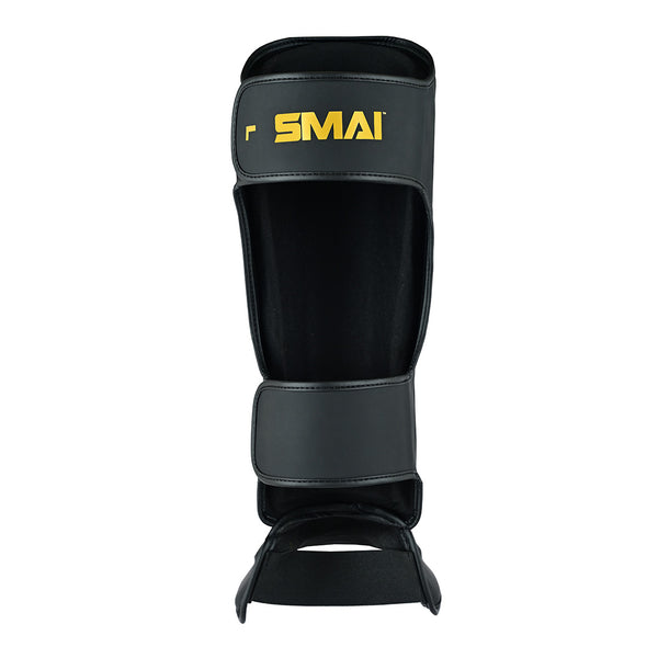 The PRE ORDER - Gold Series Muay Thai Shin Guards in Black/Gold by SMAI feature a gold logo, multi-layered shock absorption, adjustable straps, and padding for full shin and foot protection—ideal for martial arts.